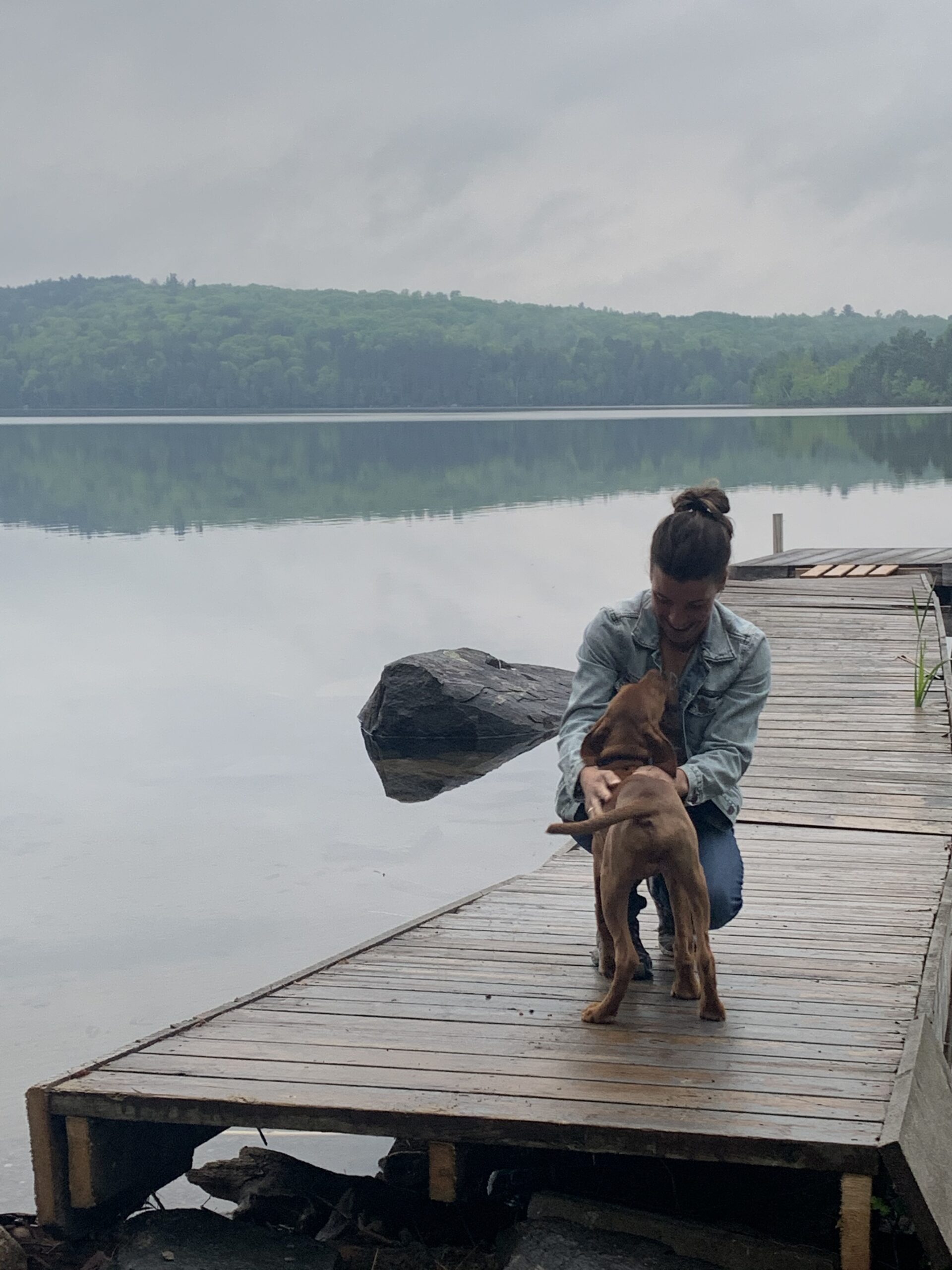 women crouching down on dog to pet her puppy